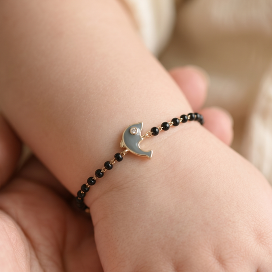 Baby wearing black bead bracelet — 14k gold dolphin kids nazariya diamond bracelet on wrist