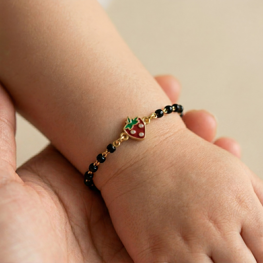 Child wearing strawberry kids nazariya — 14k gold black bead diamond bracelet for babies