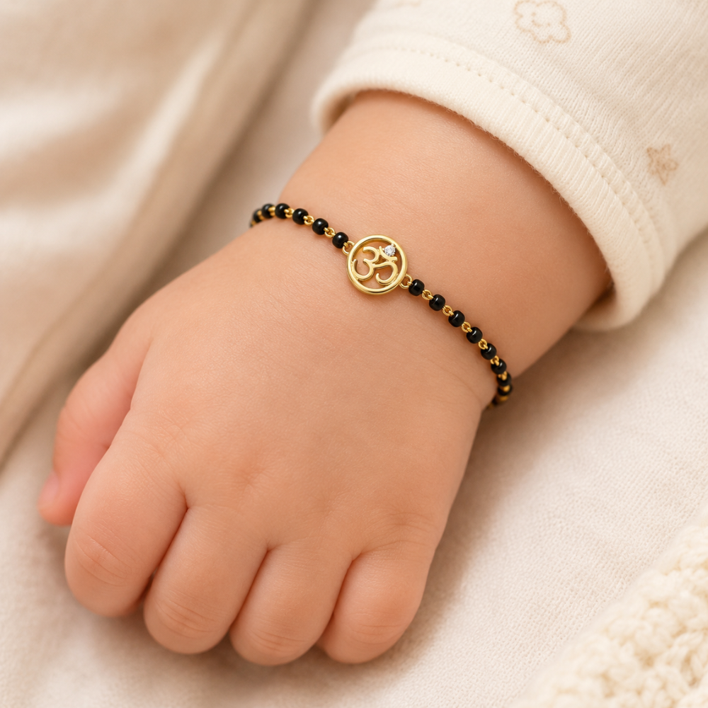 Baby wrist wearing bracelet — 14k gold kids nazariya with Om charm and black beads