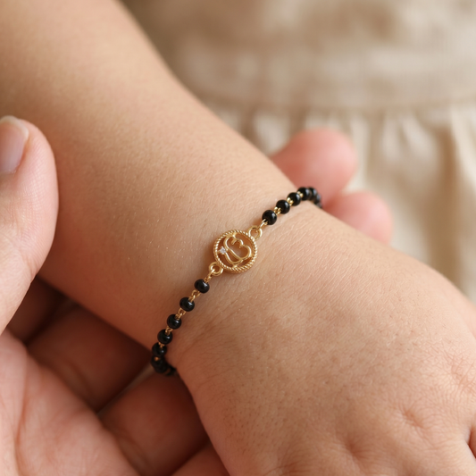 Child wearing black bead bracelet — 14k gold kids nazariya with Ik Onkar charm