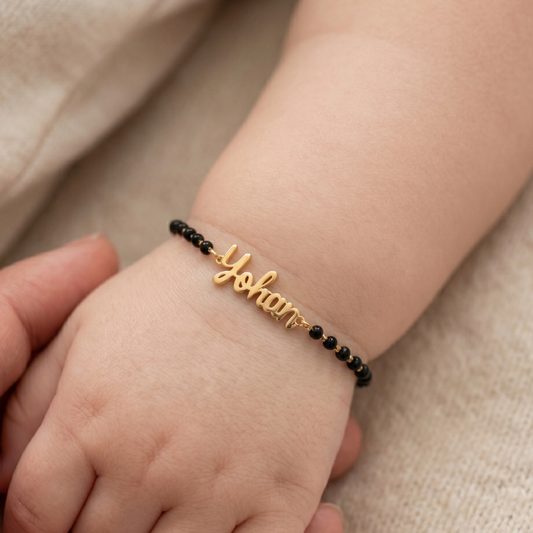 Baby wearing personalised nazariya — 14k gold baby name bracelet with black beads