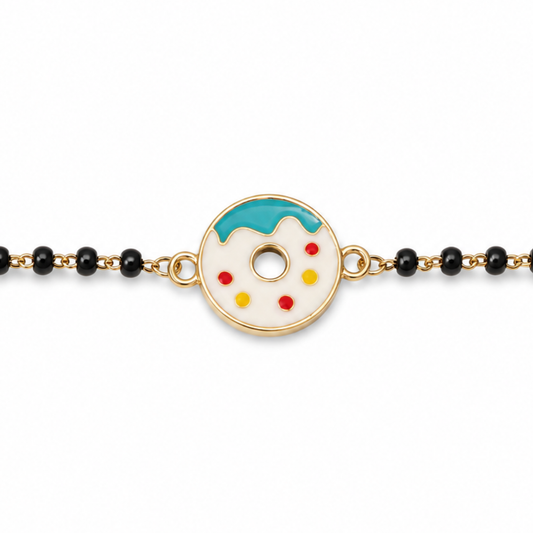 close-up of playful donut charm — 14k gold kids nazariya with enamel detail and black beads